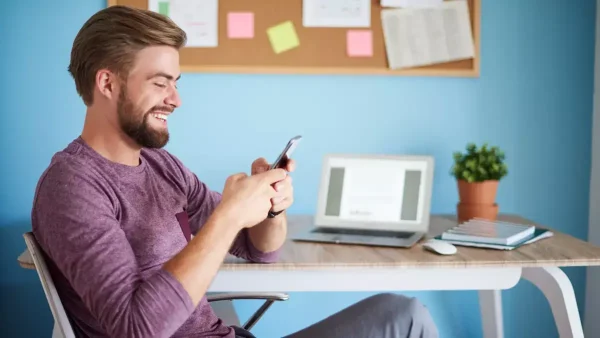 Trabajador contento en la oficina con su celular