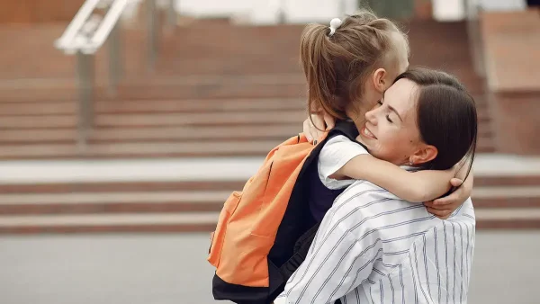 Madre despidiendo a su hija en la escuela