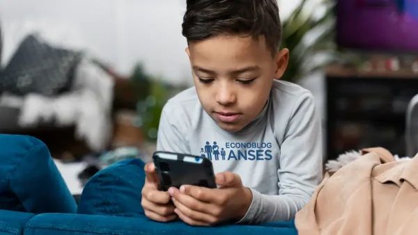 Beneficiario de la AUH con su celular y remera de Anses