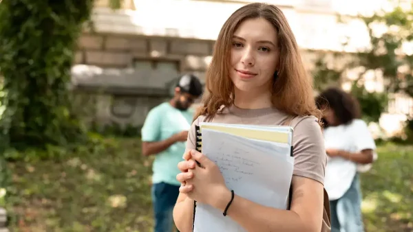 Estudiante con un cuaderno entre sus brazos