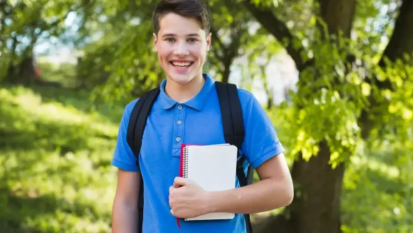 Estudiante con su mochila y un libro en la mano