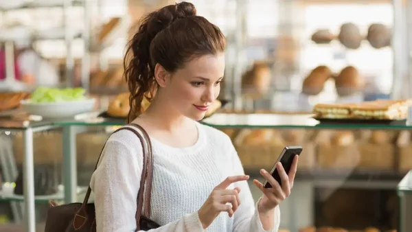 Joven mujer pagando con su celular