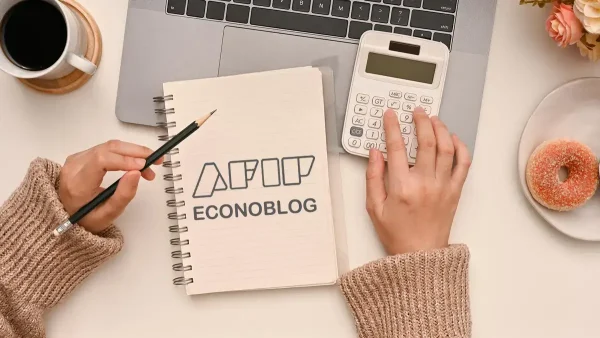 Escribiendo en cuaderno de AFIP junto a calculadora