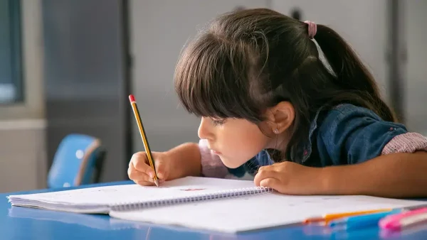 Estudiante escribiendo en el escritorio de una escuela