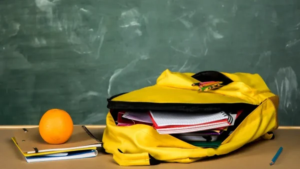 Mochila con útiles escolares y una naranja