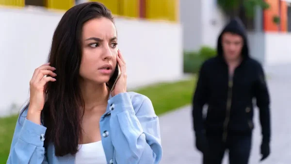 Delincuente mirando una mujer con el teléfono