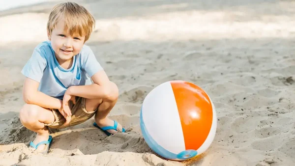 Niño jugando en la playa con una pelota