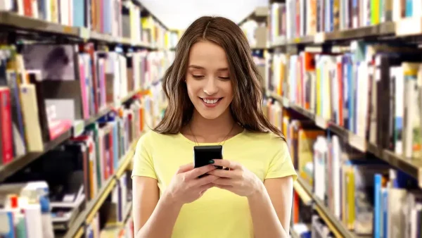 Estudiante con su celular en una biblioteca