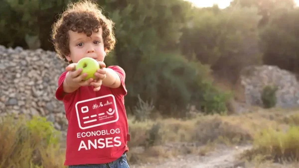 Titular de la Tarjeta Alimentar con una manzana y remera de Anses