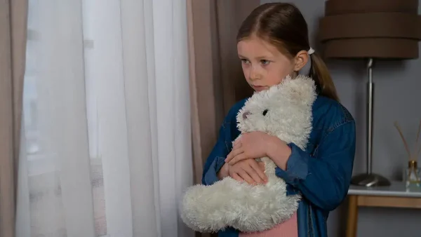Niña triste abrazada a su oso