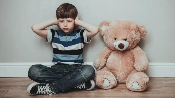 Niño triste junto a su oso