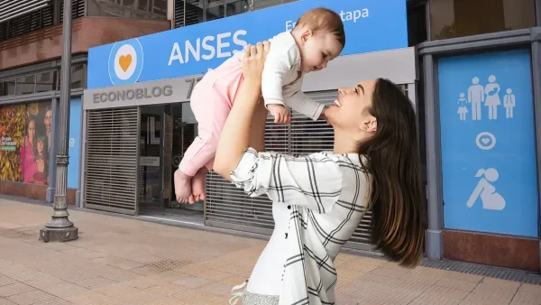 Madre y bebé en Anses con cartel de AUH y Asignación por Embarazo