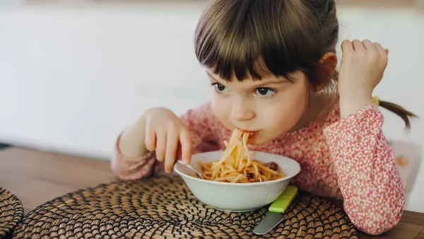 Niña comiendo fideos