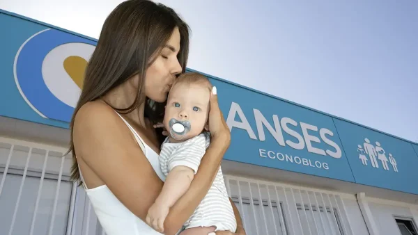 Madre con su bebé con cartel de Anses para AUH