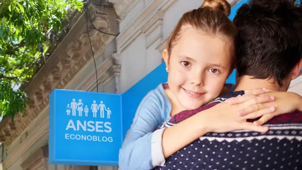 Abrazo de padre frente a cartel de Anses para AUH y SUAF